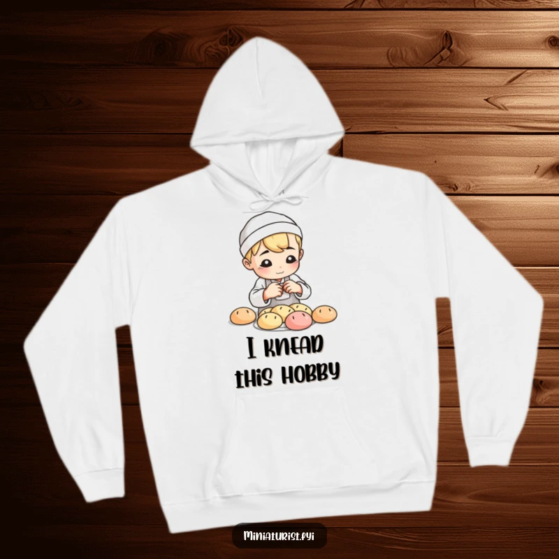 Funny Baker Loaf Hoodie, cozy sweatshirt with a small baker shaping tiny clay bread loaves with playful concentration, for bakers.